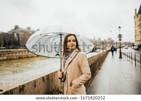 Portrait of girl with an transparent umbrella on which is drawn Eiffel tower. It is raining outside. Beautiful portrait.