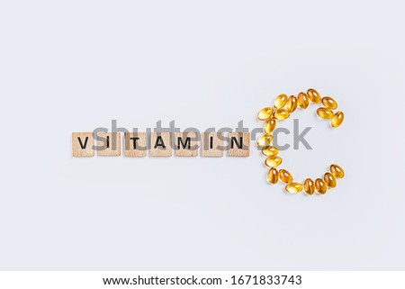 letter C made from transparent pills near the inscription Vitamin on a white background