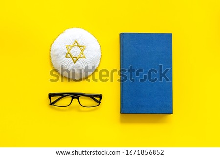 Jewish Kippah Yarmulkes hats with Star of David with Prayer book. Religion Judaisim symbols on yellow table. Top view, space for text