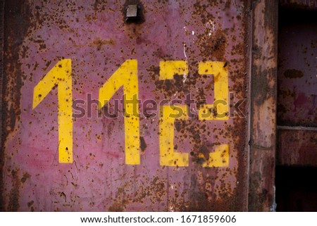 
Metallic textured rusty wall of red color with numbers and phone icon
