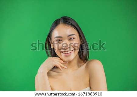 Asian woman smiling and looking at camera isolated on green background