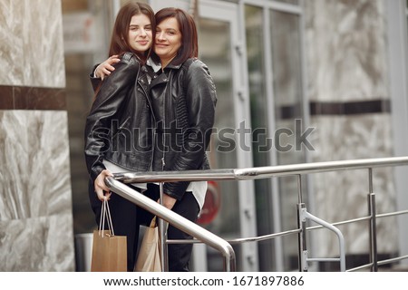 Women on a gray building background. Ladies with shopping bags. Mother with daughter.