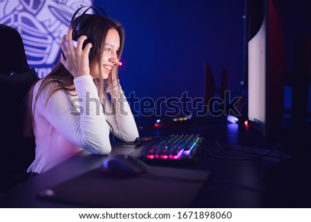 Streamer beautiful girl professional gamer playing online games computer with headphones, red and blue color.