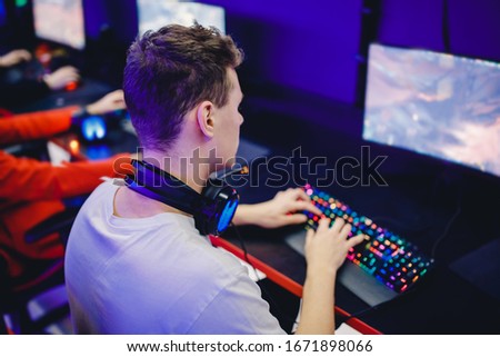 Friends young guys play online video games with headphones in an internet club cafe. Esports team concept.