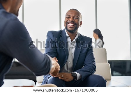 Two happy mature business men shaking hands in office. Successful african american businessman in formal clothing closing deal with handshake. Multiethnic businessmen shaking hands during a meeting. Royalty-Free Stock Photo #1671900805
