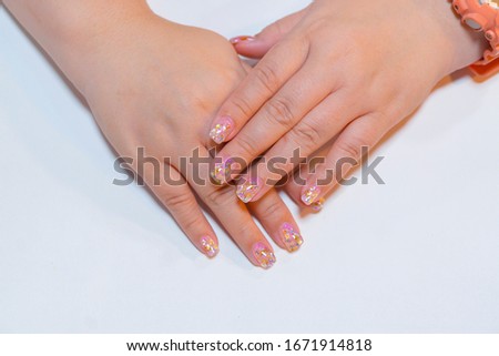 Trendy crack shell decorated on woman short fingernail with sparkling silver and gold glitter in clear gel nail art isolated on white background