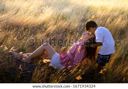 The son showed love for his mother. By kissing on the forehead of the mother at the meadow in the evening