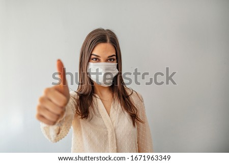 Portrait of young woman wearing face protective mask to prevent Coronavirus and anti-smog. Portrait of young woman wearing face mask. Thumb up.  Royalty-Free Stock Photo #1671963349
