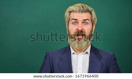 Teaching for surprise. Surprised teacher at green chalkboard. Bearded man keep mouth opened of surprise. School and education. Bringing surprise element into lesson. Surprise concept, copy space.