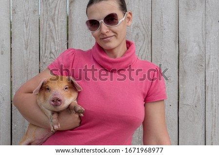 Young girl in pink sweatshirt and sunglasses is holding red pig