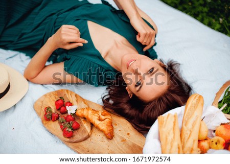A girl is lying in the Park on a picnic with snacks, strawberries and croissants. Freshness and holidays.