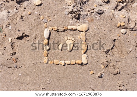 Sand texture. Sandy beach with sea  stones for background.Touching picture of sea pebbles on  sandy beach. Image of a child's and adult's foot made of stones.