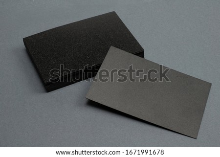 stack of black blank textured business cards on dark paper background, us size 3.5 x 2 inches, as template for design presentation.