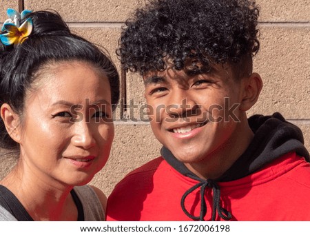 Asian mother with her African American mixed race teenage son.  Mixed race mother and teenage son close up smiling.