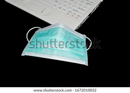 Dust mask and corona virus and laptop isolated on a black background