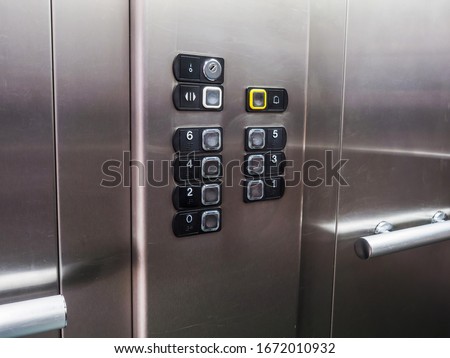 Elevator lift buttons, modern stainless steel interior.