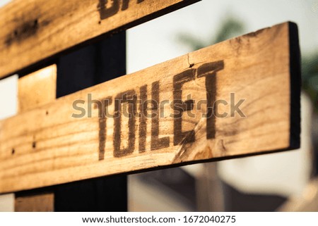 Closeup toilet sign made by wood plank on the post, outdoor toilet sign