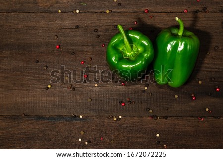 Two bell green peppers on a wooden background