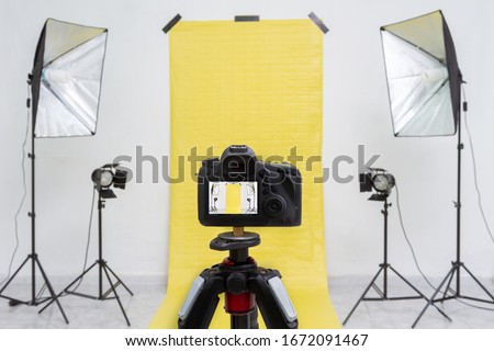 Dslr camera in a photo studio with yellow backdrop and light equipment