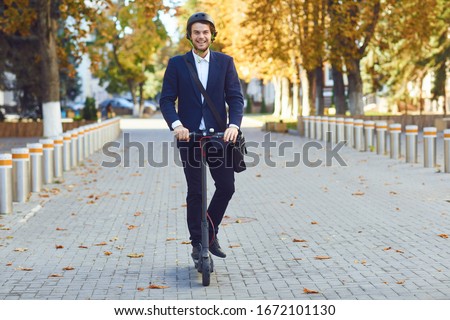 Young man in a helmet rides an electric scooter on a city street in summer Royalty-Free Stock Photo #1672101130