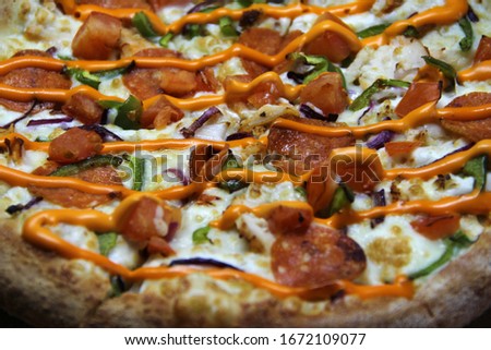 Pizza with slices of pepperoni and pepper, topped with cheese and hot orange sauce on a craft cardboard background, side view. Stock photo for web and print.