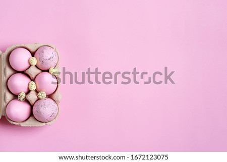 Festive Easter frame from paper box of handmade pink painted eggs on a same color background.