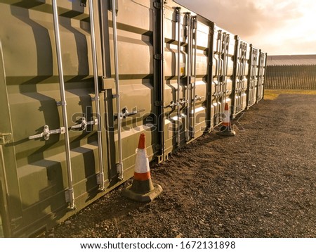 A row of storage containers with the sun setting in the background.