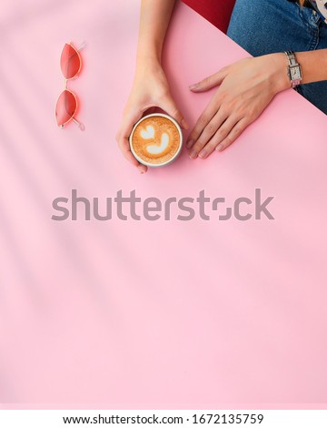 Girl's hands hold a coffee cup on a pink background. Flat lay, top view. Take away.