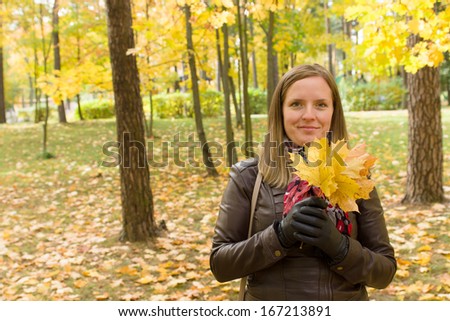 young beautiful girl holding autumn leaves