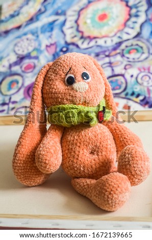 Knitted bunny toy apricot color on a picturesque background. Easter photo.