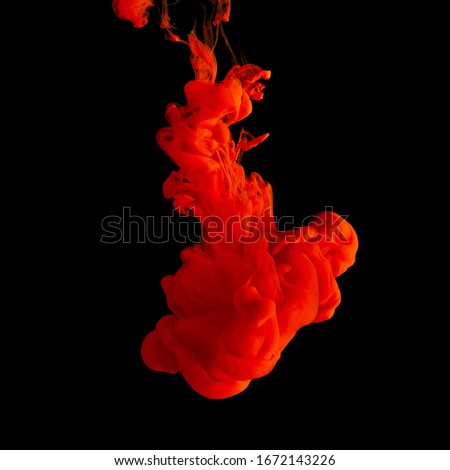 Red acrylic Ink splashes in water on black backdrop. Minimal abstract background.