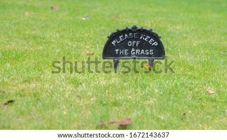 "please keep off the grass"  warning sign in the park 