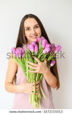Close up portrait of a young beautiful smiling girl with a bouquet of flowers, in bloom. Bright spring colors. Horizontal picture on white background
