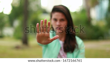 Woman annoyed making stop sign with hand, saying no, expressing defense or restriction