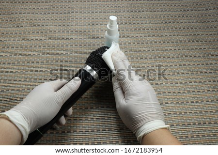 Cleaning staff clean karaoke microphone in studio room with alcohol spray and wipe out with clean paper. Corona Virus or bacteria infected protection from touching public object.  Royalty-Free Stock Photo #1672183954