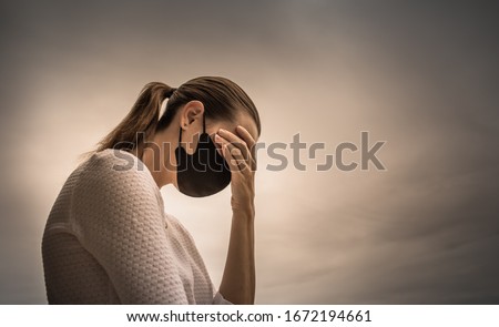 Stressed female wearing protective face mask. Coronavirus, fear, and mental health concept.    Royalty-Free Stock Photo #1672194661