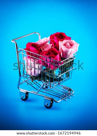 Roses in shopping cart on blue background.