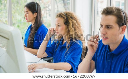 Customer support operator at work. Team Business and Delivery call center in office. Working with a headset in blue uniform.