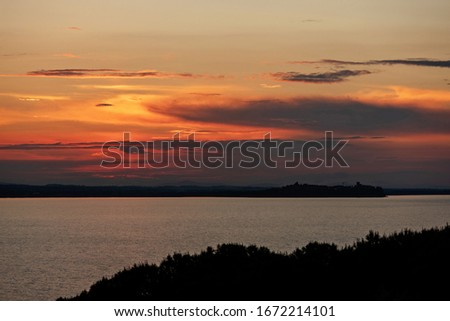 Summer sunset on Lake Trasimeno in Umbria with Castiglione del Lago on background