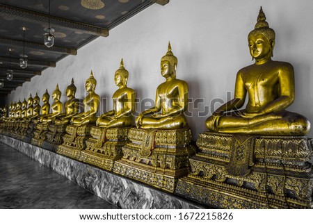 Row of golden buddhist statues in a temple in Bangkok, Thailand. Royalty free stock photo.