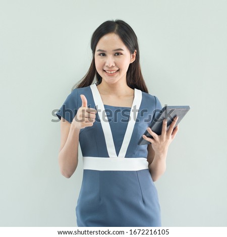 Portrait of young happy asian businesswoman using digital tablet and trump up isolated over white background in work place.