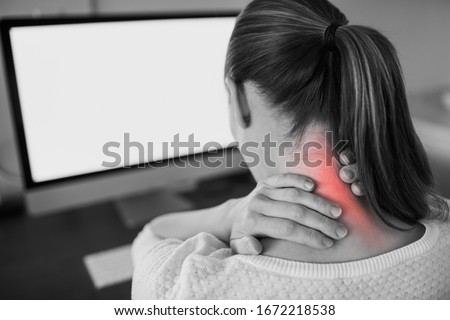 Neck ache concept. Young woman sitting at office desk feeling hurt having pain in her neck.Woman massaging rubbing stiff sore neck tensed muscles, fatigued from computer work and incorrect posture. Royalty-Free Stock Photo #1672218538