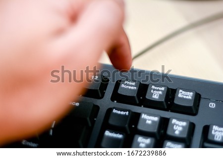 Close up point finger is pressing print screen command on the keyboard. Modern and fresh image.