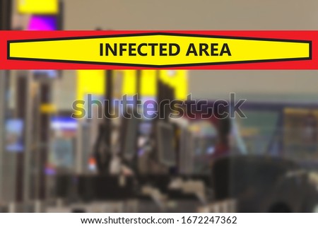 Blurred computer terminals at airport gate desks with a banner warning that the area is infected