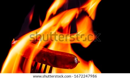 Grilling sausage on black background