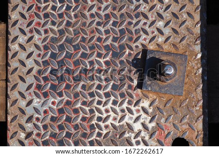 Old dirty red  black steel sheet metal plate with embossed diamond pattern used for flooring and industrial construction.  close up of old rusty sheet metal nuts and iron plate.  