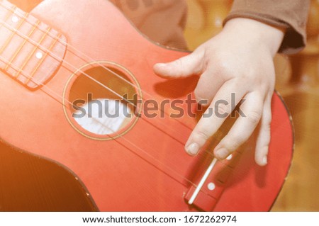 The child plays a children's guitar. Hand on musical instrument. A toy