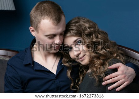 The guy and the girl are sitting embracing. A young couple. Lovers. A man takes on a beautiful woman.