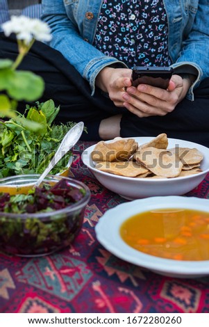 Woman take picture of food with phone at kitchen or summer cafe. Smartphone photography of Indian chapati naan flatbread for blogging or social media publications. Vegan vegetarian healthy diet.