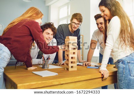 Young people have fun playing board games at a table in the room.